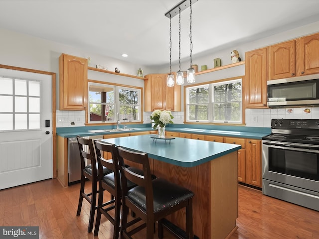 kitchen with backsplash, a kitchen bar, plenty of natural light, and appliances with stainless steel finishes
