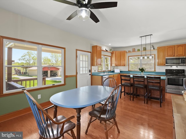 dining space featuring light wood-style flooring, a wealth of natural light, baseboards, and ceiling fan