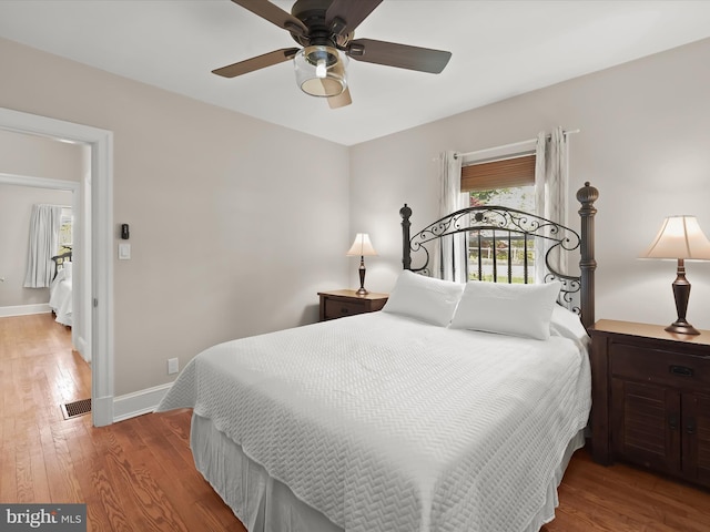 bedroom with wood finished floors, a ceiling fan, baseboards, and multiple windows