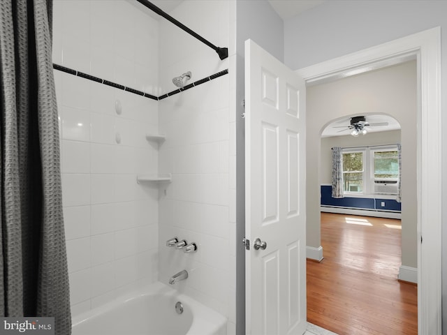 full bath featuring wood finished floors, a ceiling fan, shower / tub combo with curtain, baseboards, and a baseboard radiator