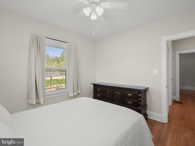 bedroom with visible vents, baseboards, a ceiling fan, and wood finished floors