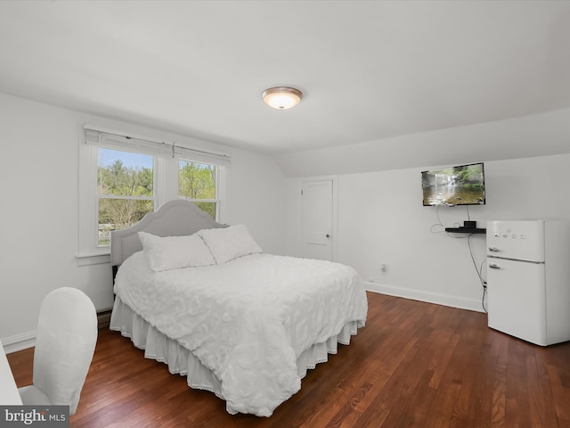 bedroom featuring dark wood-type flooring, freestanding refrigerator, and baseboards