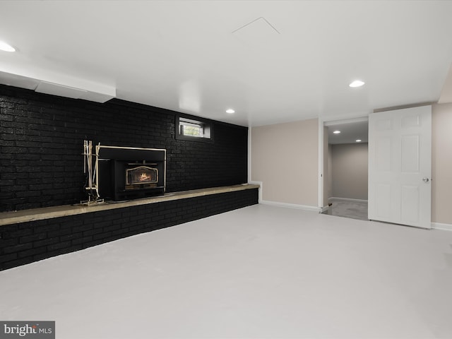 below grade area with recessed lighting, brick wall, baseboards, and a lit fireplace