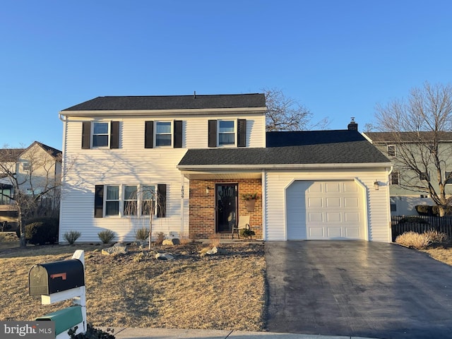 traditional-style home with a garage, aphalt driveway, a chimney, and brick siding