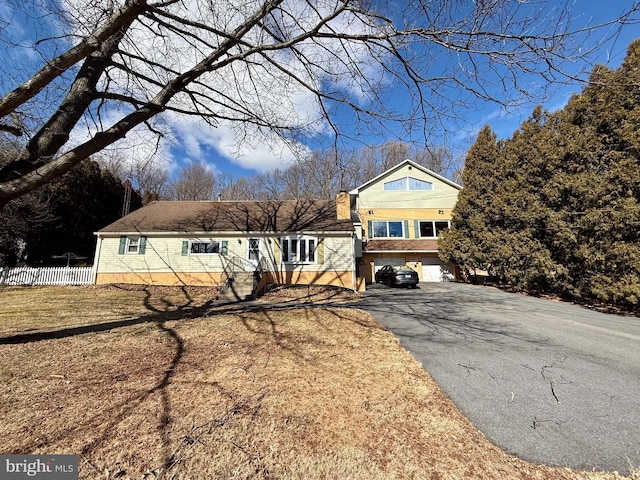 view of front facade with aphalt driveway and fence