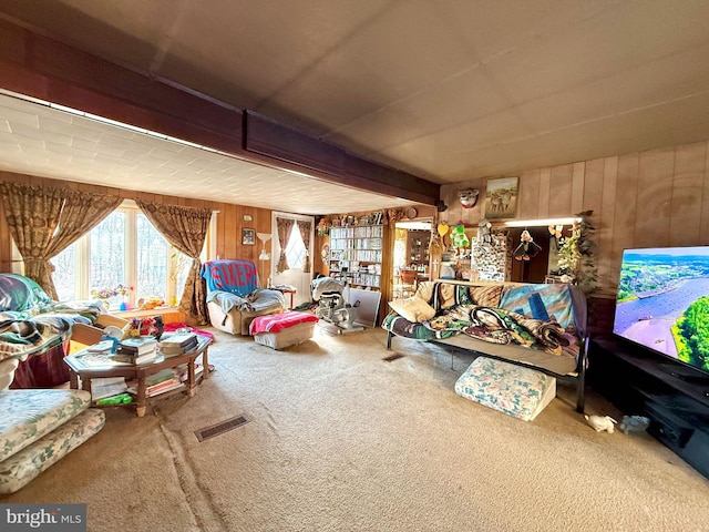 interior space with beamed ceiling, wood walls, carpet flooring, and visible vents