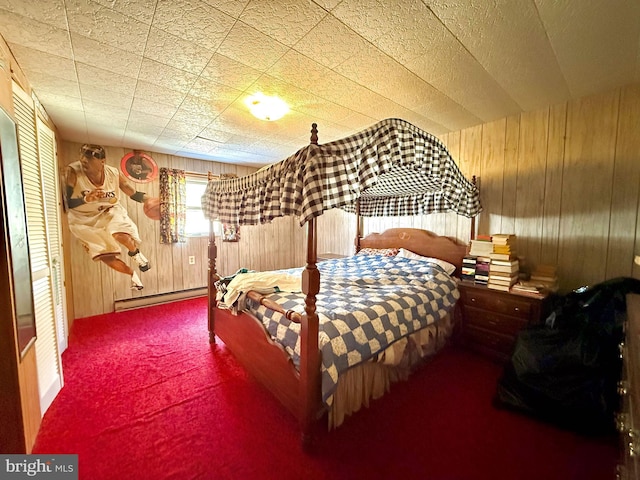 bedroom featuring carpet floors, wood walls, and baseboard heating