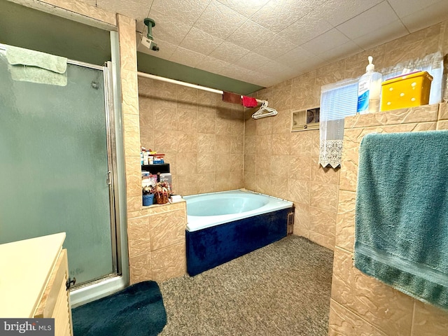 full bath with a bath, a stall shower, and tile walls