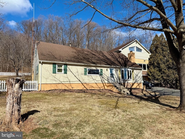 view of front of property featuring a shingled roof, fence, and a front lawn