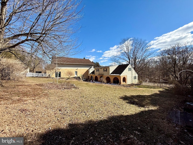 back of house featuring fence and a lawn