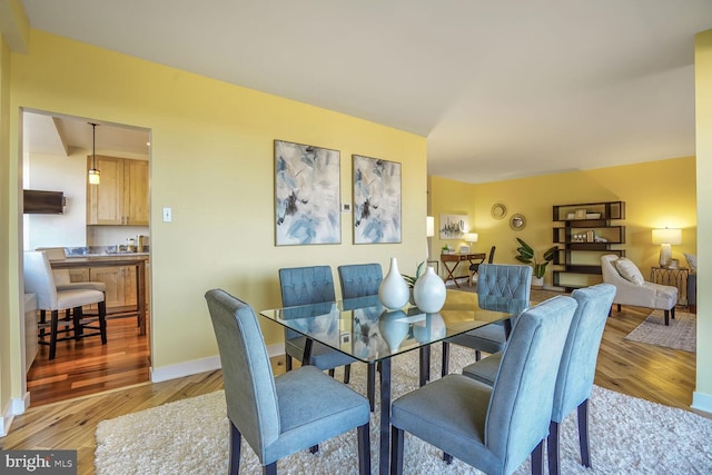 dining area featuring light wood-style flooring and baseboards