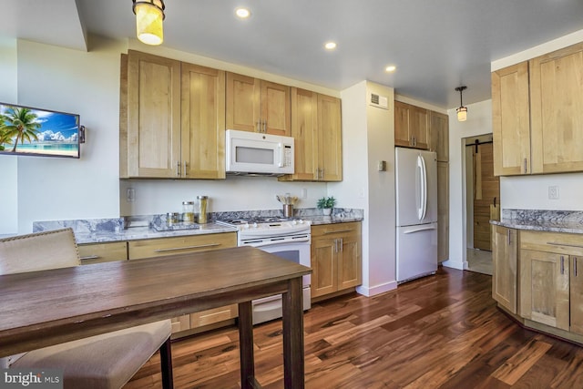 kitchen featuring dark wood finished floors, visible vents, a barn door, light stone countertops, and white appliances