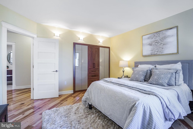 bedroom with a closet, wood finished floors, and baseboards