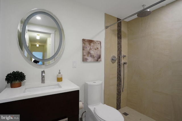 bathroom featuring vanity, a tile shower, and toilet