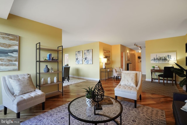 living area with track lighting, baseboards, and wood finished floors