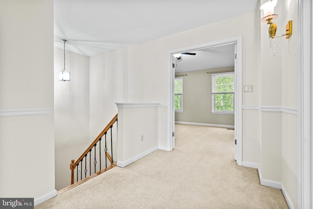 hall featuring baseboards, carpet, and an upstairs landing