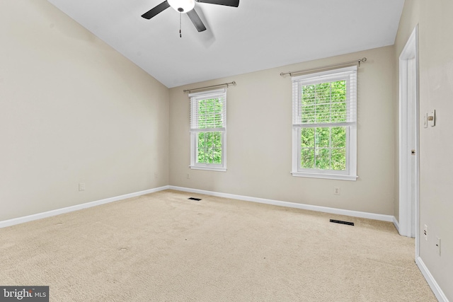 empty room with visible vents, carpet, a ceiling fan, baseboards, and vaulted ceiling