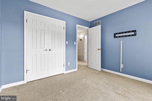 unfurnished bedroom with carpet floors, baseboards, visible vents, and a closet