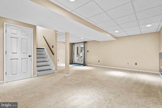 finished basement featuring carpet floors, baseboards, a drop ceiling, and stairs