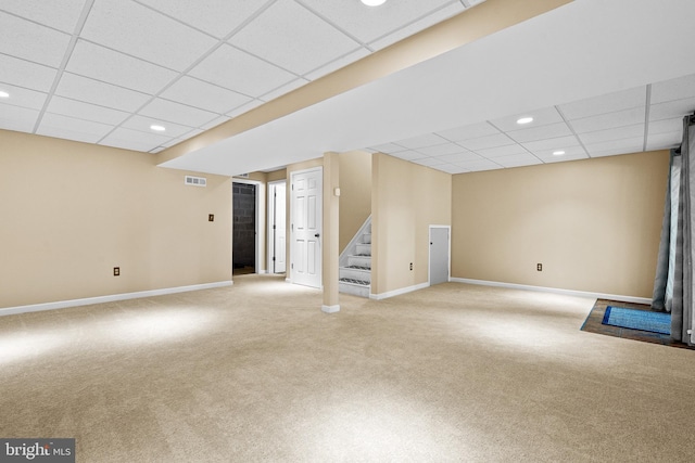 finished basement featuring stairway, visible vents, a drop ceiling, and light colored carpet