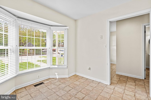 empty room with baseboards, visible vents, and a healthy amount of sunlight