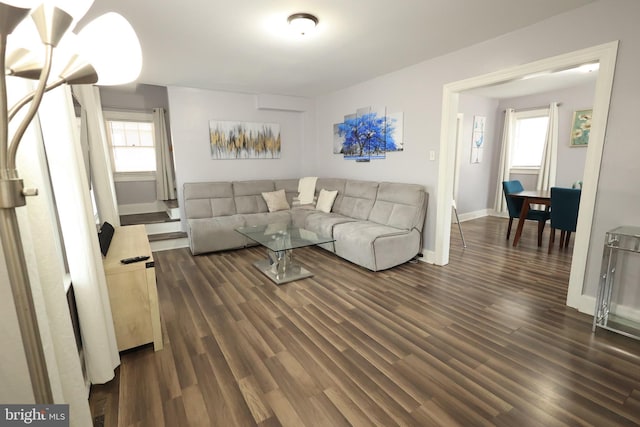 living area with dark wood-style floors, plenty of natural light, and baseboards