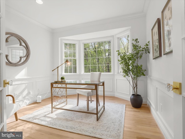 home office featuring crown molding, light wood-style floors, and a decorative wall