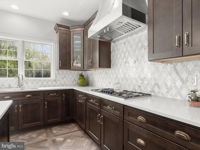 kitchen featuring light countertops, stainless steel gas stovetop, a sink, and ventilation hood