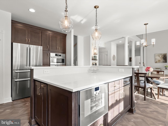 kitchen featuring light countertops, appliances with stainless steel finishes, dark brown cabinetry, and decorative light fixtures