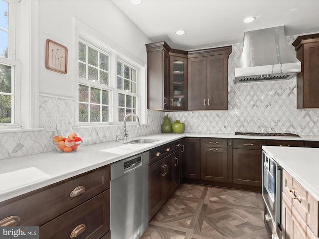 kitchen featuring a sink, appliances with stainless steel finishes, wall chimney exhaust hood, and a healthy amount of sunlight