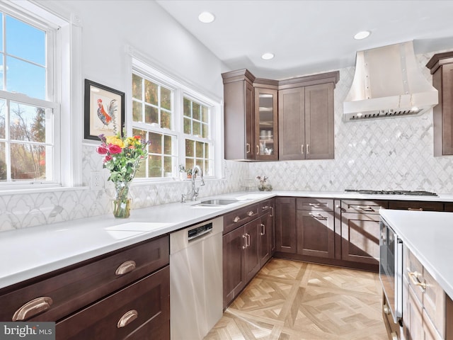 kitchen with a sink, light countertops, stainless steel appliances, custom exhaust hood, and glass insert cabinets