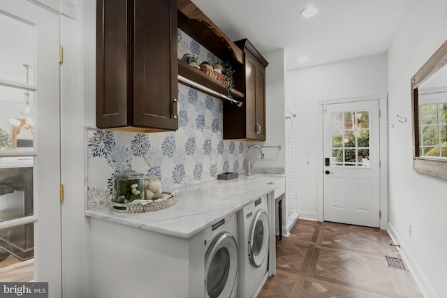 laundry area featuring cabinet space, washing machine and clothes dryer, a sink, baseboards, and visible vents