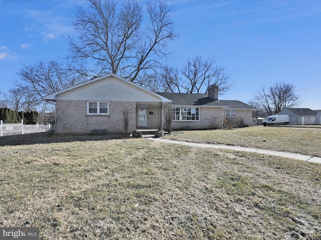 ranch-style house featuring a front yard, brick siding, fence, and a chimney