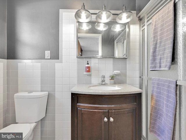 bathroom featuring toilet, vanity, and tile walls