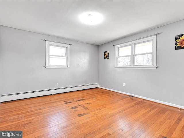 empty room featuring hardwood / wood-style flooring, baseboards, and a baseboard heating unit