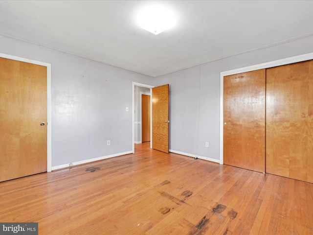 unfurnished bedroom featuring a closet, wood-type flooring, and baseboards