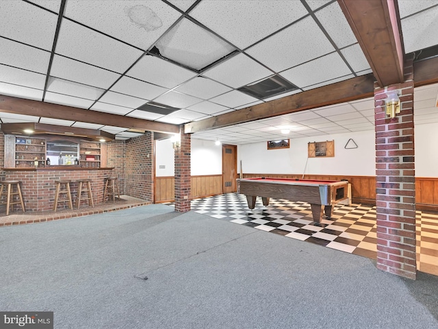 interior space featuring a wainscoted wall, wooden walls, a bar, and ornate columns