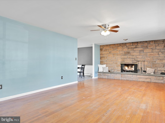 unfurnished living room with a ceiling fan, a fireplace, baseboards, and wood finished floors