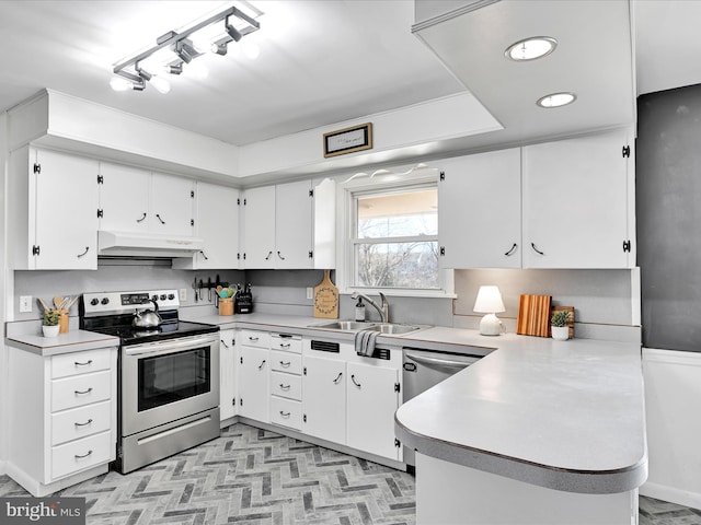 kitchen with under cabinet range hood, a peninsula, a sink, light countertops, and appliances with stainless steel finishes