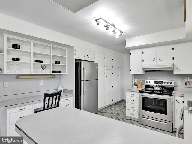 kitchen featuring white cabinets, appliances with stainless steel finishes, under cabinet range hood, open shelves, and built in desk