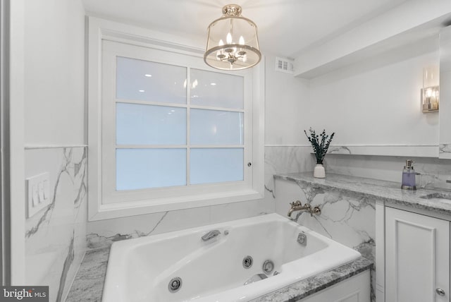 full bath with a jetted tub, a sink, visible vents, and a notable chandelier