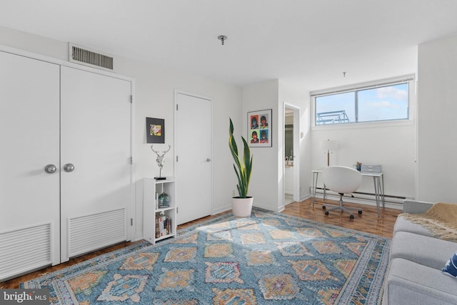 interior space featuring baseboards, visible vents, baseboard heating, and wood finished floors