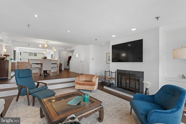 living room with a chandelier, a glass covered fireplace, recessed lighting, and wood finished floors