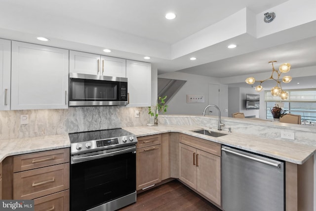 kitchen featuring stainless steel appliances, white cabinetry, a sink, and a peninsula