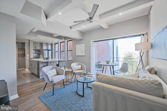 living area with a wealth of natural light, beamed ceiling, baseboards, and wood finished floors