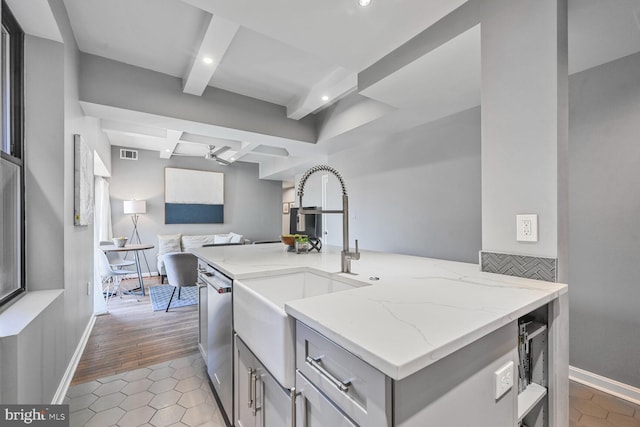 kitchen featuring visible vents, gray cabinetry, open floor plan, beamed ceiling, and light stone counters