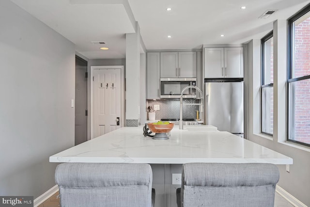 kitchen featuring a wealth of natural light, visible vents, gray cabinets, and appliances with stainless steel finishes