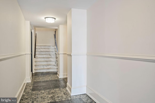 hallway with stone finish flooring, stairs, and baseboards