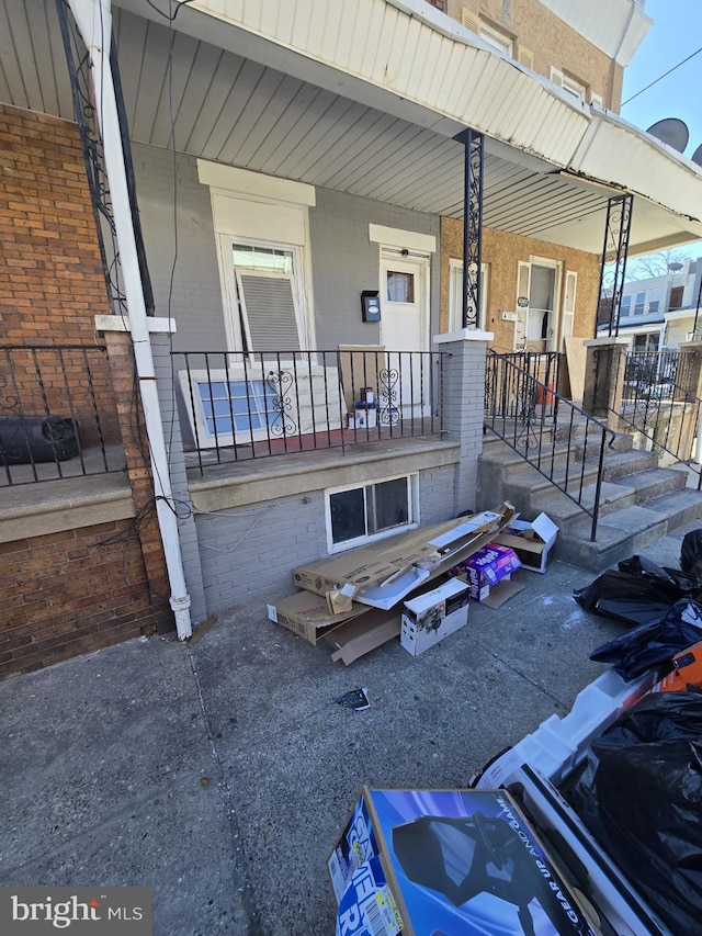 exterior space with a porch and brick siding