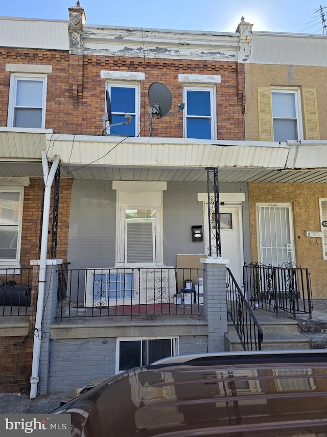 view of property with a porch and brick siding